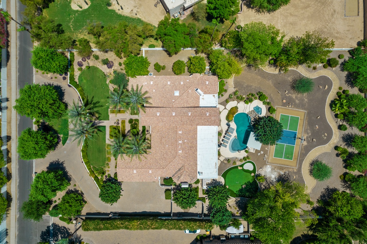 Top-down aerial shot of the property showing the house, pool, sport court, and surrounding landscaping.