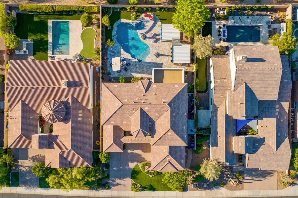 Aerial view of three neighboring Arizona homes with landscaped backyards, pools, and neatly arranged greenery.