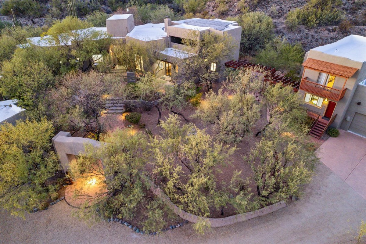 Desert home with flat roof surrounded by cacti and mountains