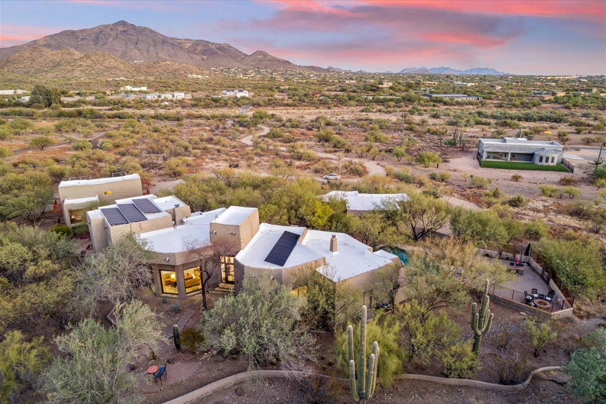 Desert home with flat roof surrounded by cacti and mountains