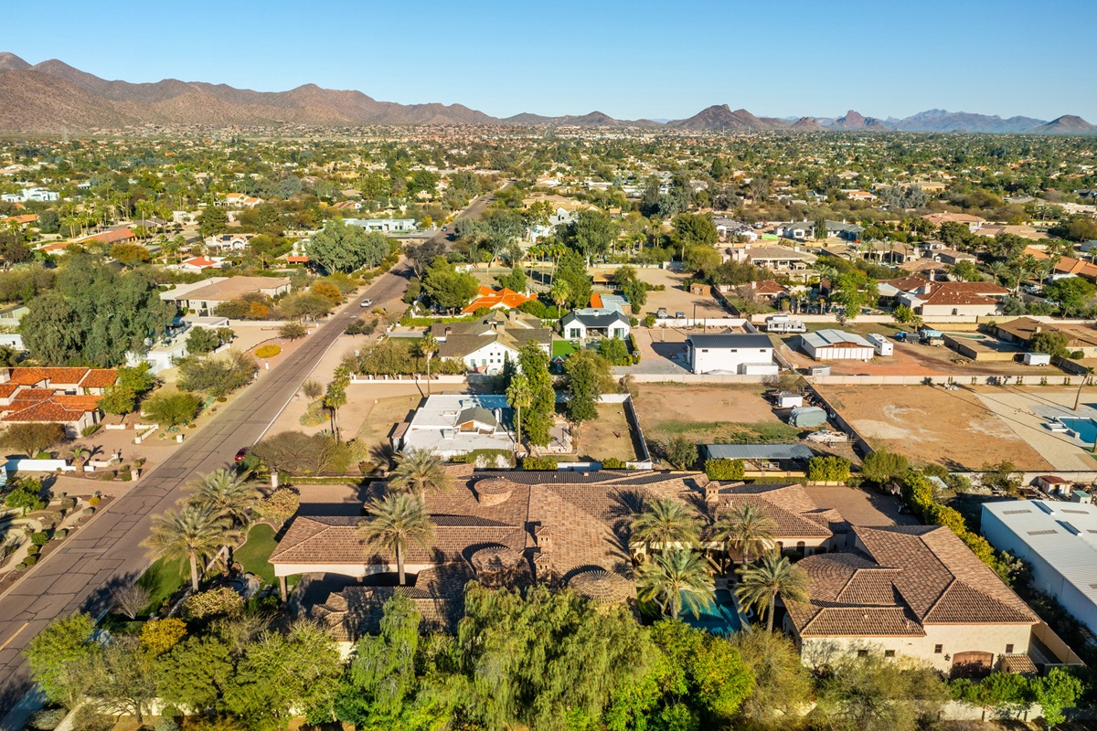 Suburban desert neighborhood with single-story homes, palm trees, and mountains in the distance.