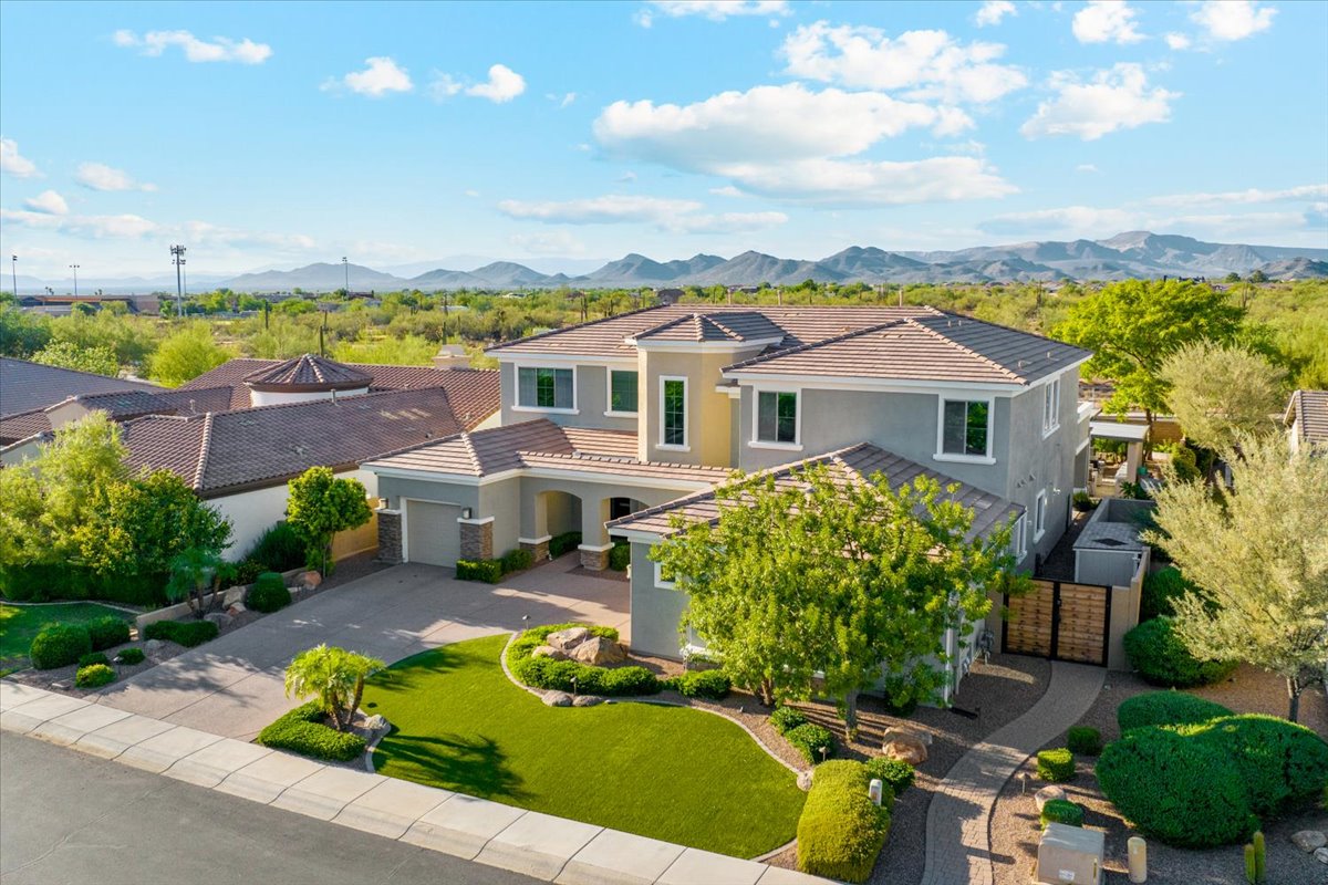 Suburban two story home with mountain backdrop and desert landscaping.