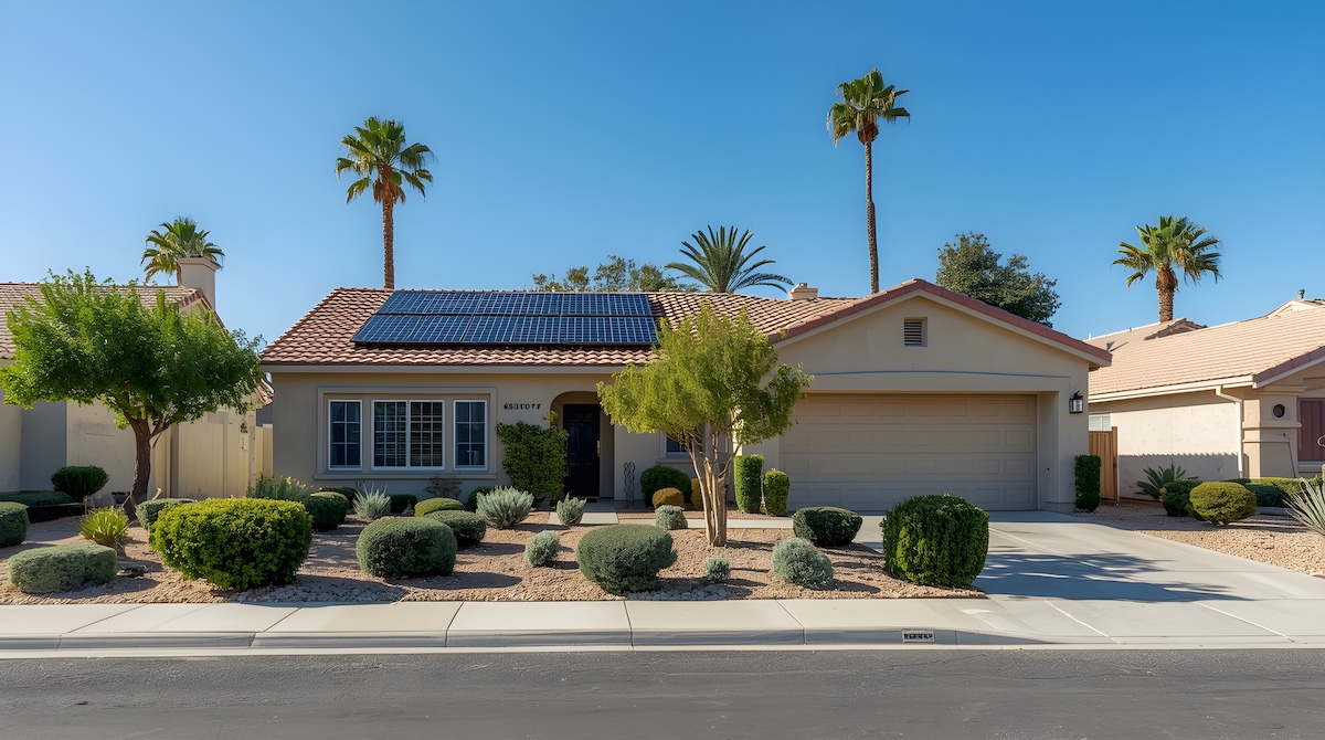 single family home with a tiled roof and solar panels on the roof surrounded by lush green landscaping and palm trees under a clear blue sky