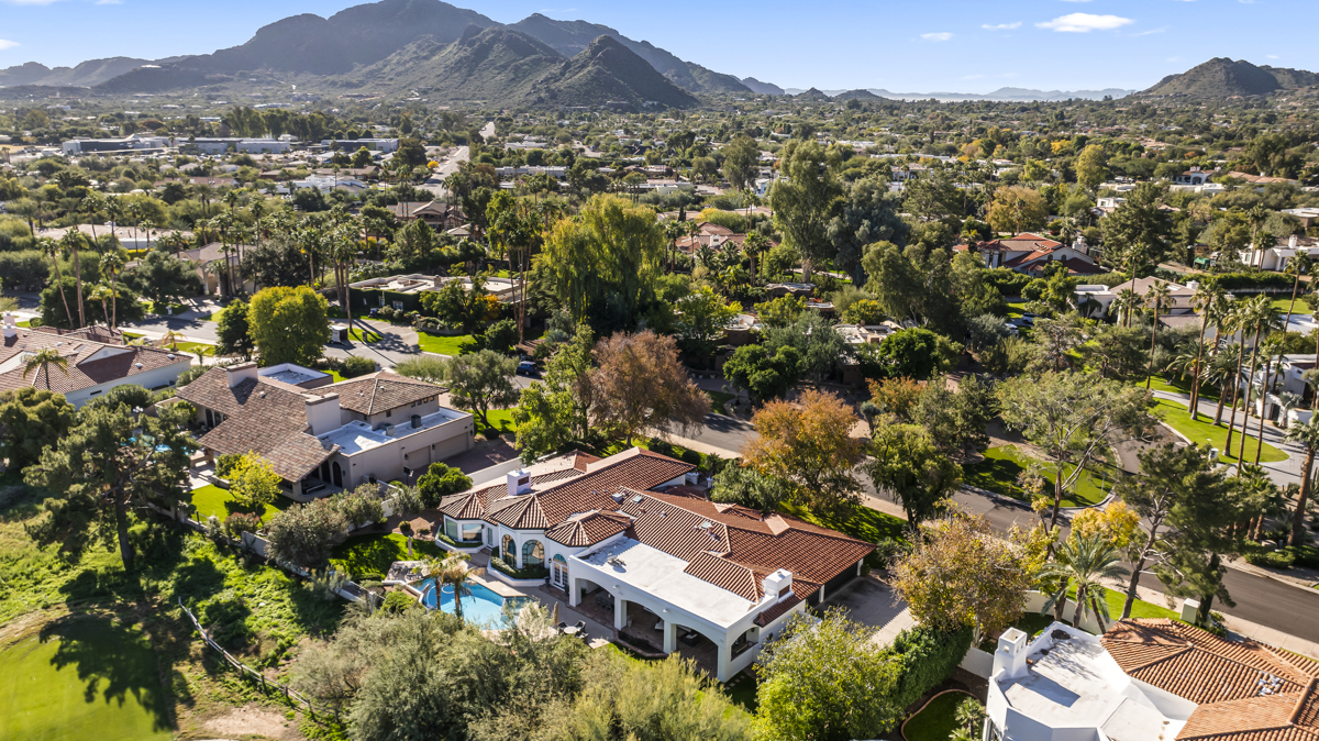 Aerial view of luxury homes with pools and lush landscaping in Paradise Valley, set against scenic desert mountains.