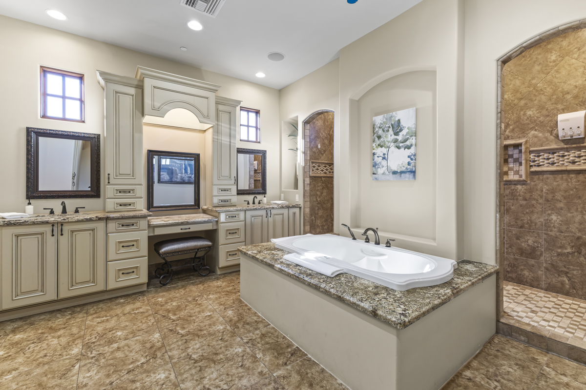 Spacious bathroom with granite counters, built-in cabinetry, soaking tub, and tiled walk-in shower.