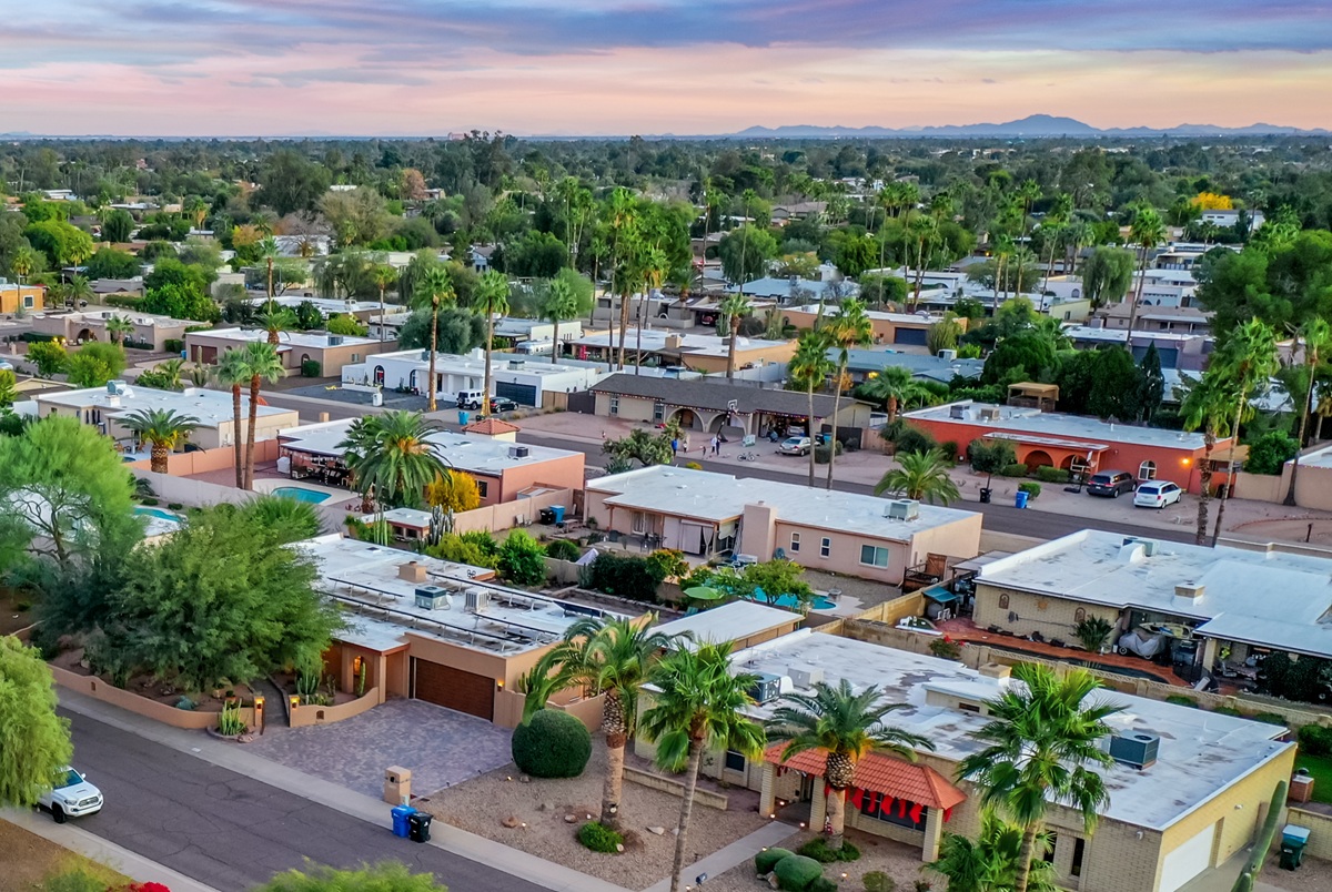 Residential Phoenix neighborhood with single-story homes, palm trees, and desert landscaping at sunset.