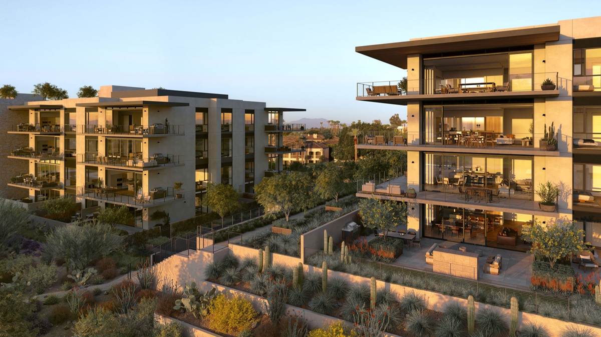 Multi-story modern residential buildings with spacious balconies, landscaped desert grounds, and warm evening light.