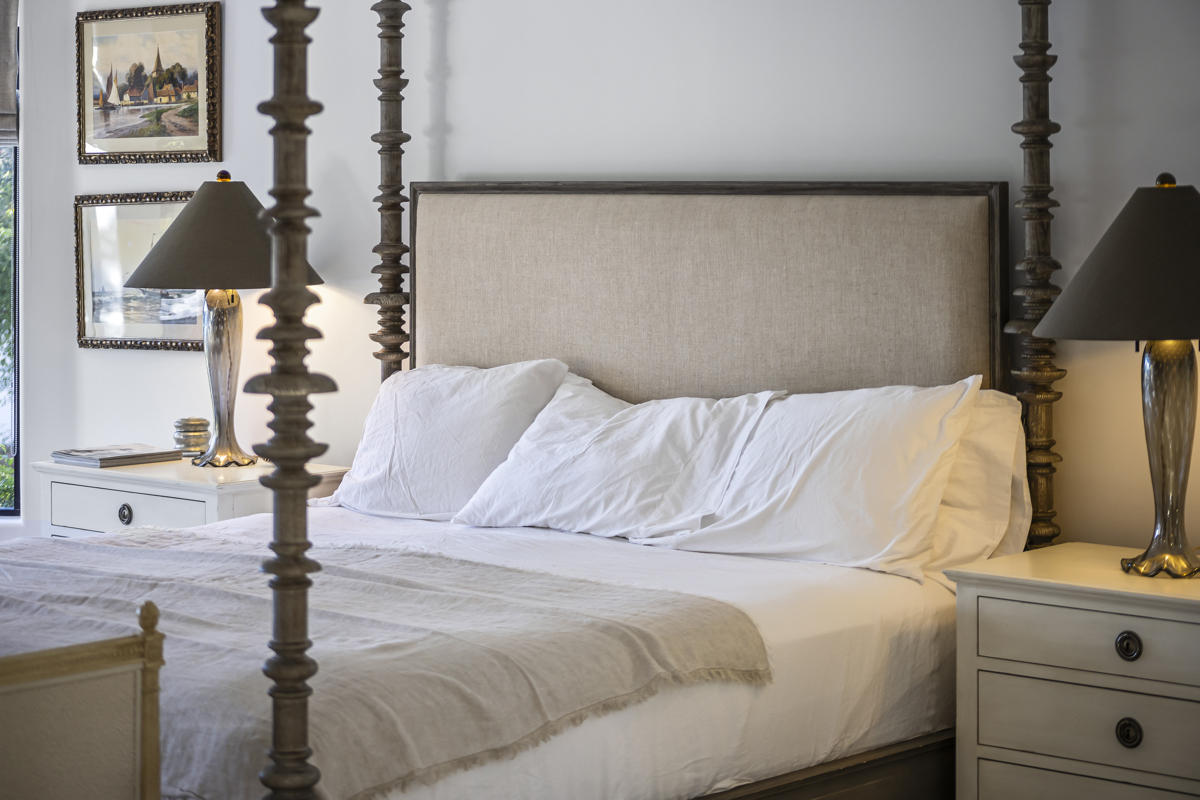 Bright bedroom with a four-poster bed, white bedding, and matching bedside lamps.