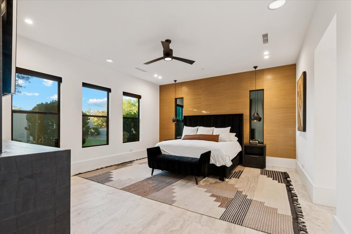 Modern luxury bedroom with wood accent wall and black furnishings.