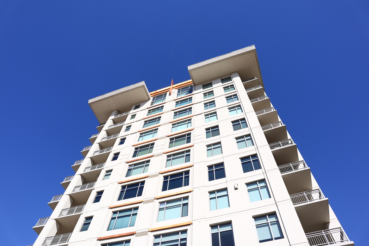Luxury condominium building rising beneath a clear blue sky.