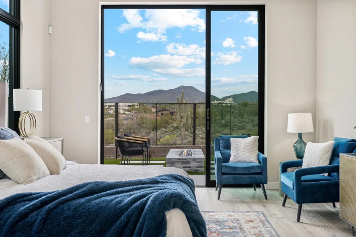 Bedroom with blue furnishings, a private patio, and desert mountain views.