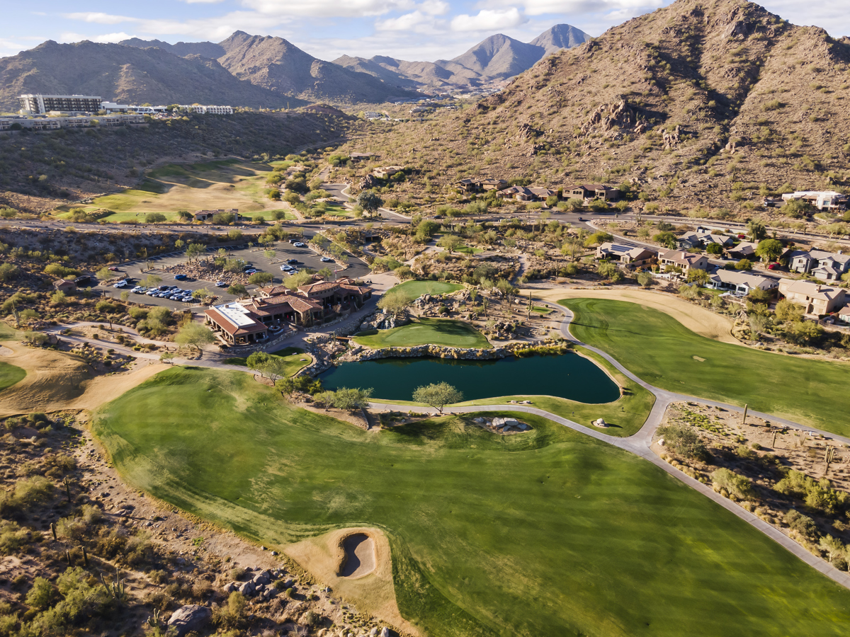 An aerial view of an Arizona golf community surrounded by dramatic desert mountains.