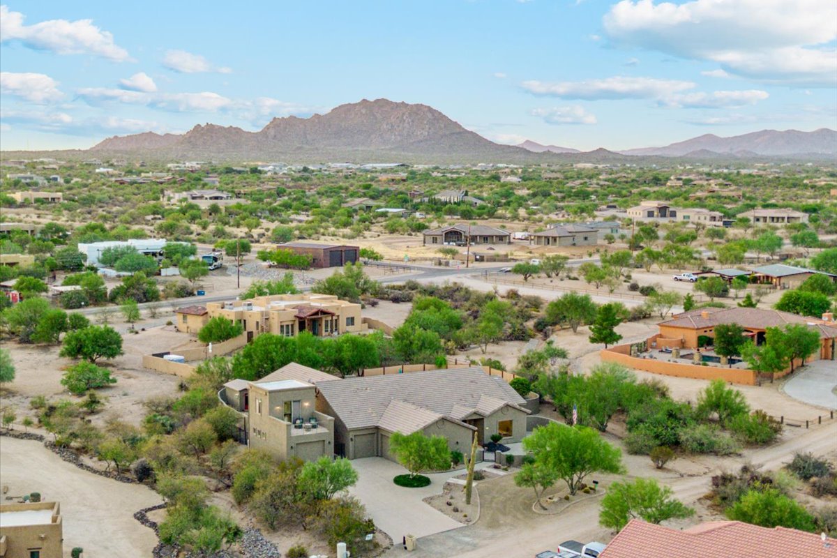 An aerial view of an Arizona residential neighborhood with desert homes and mountain views.