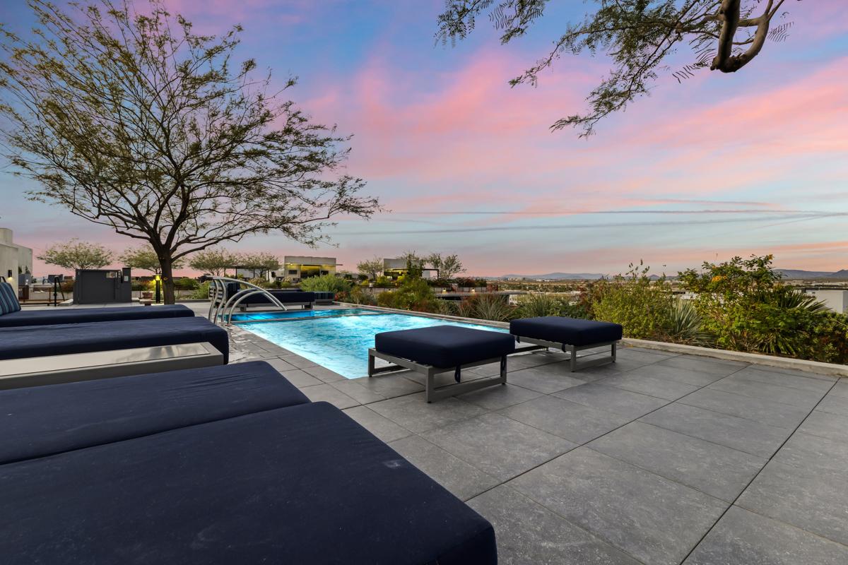 Luxury pool terrace beneath a colorful desert sunset.