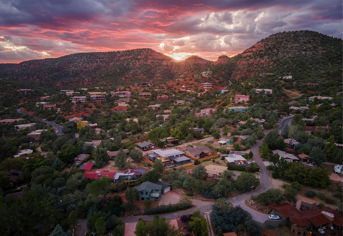 Sedona neighborhood surrounded by red rock formations at sunset.