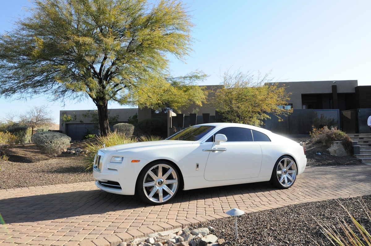White Rolls-Royce parked in front of a modern Scottsdale luxury home.