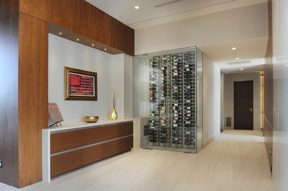Modern luxury interior with wood cabinetry and a glass-enclosed wine display.