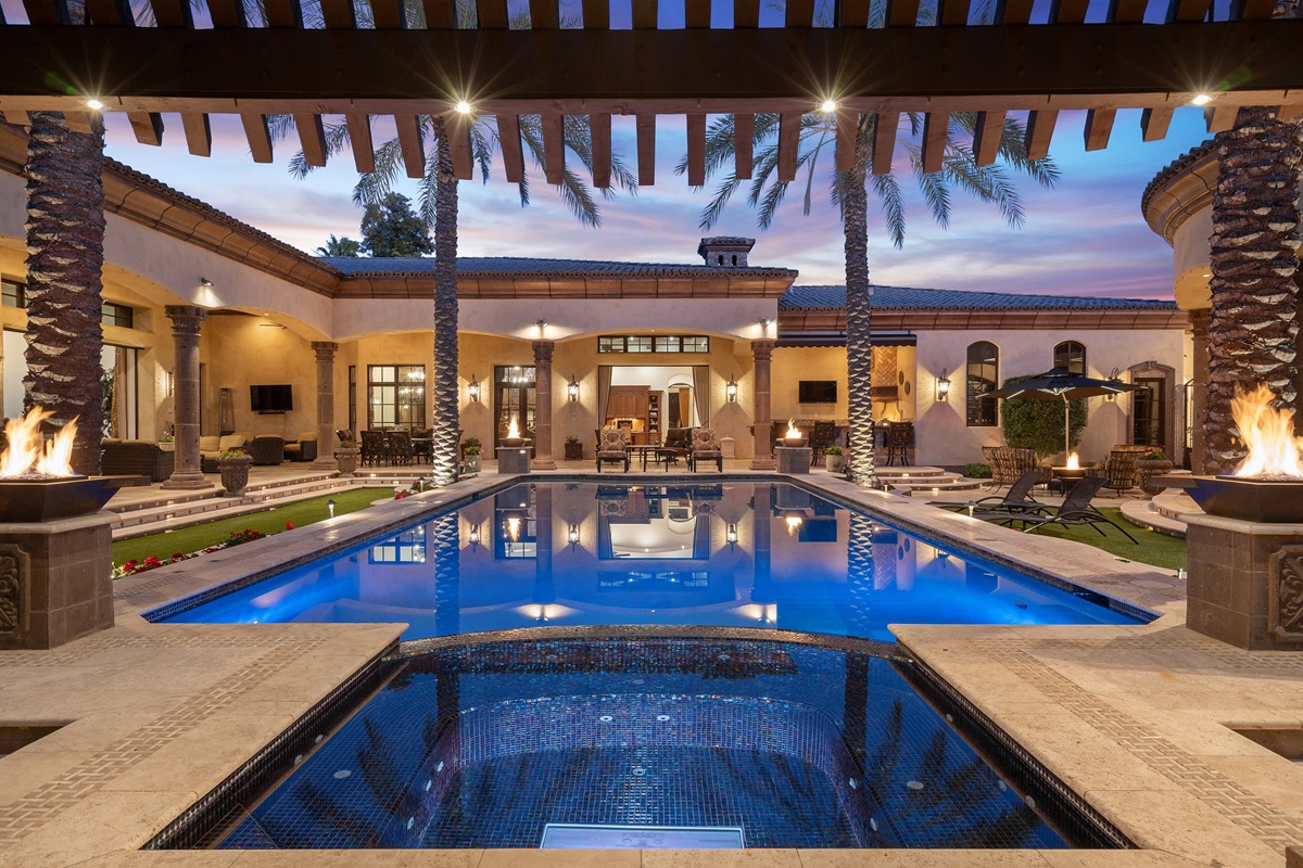 Luxury Scottsdale backyard with a glowing pool and fire features at sunset.