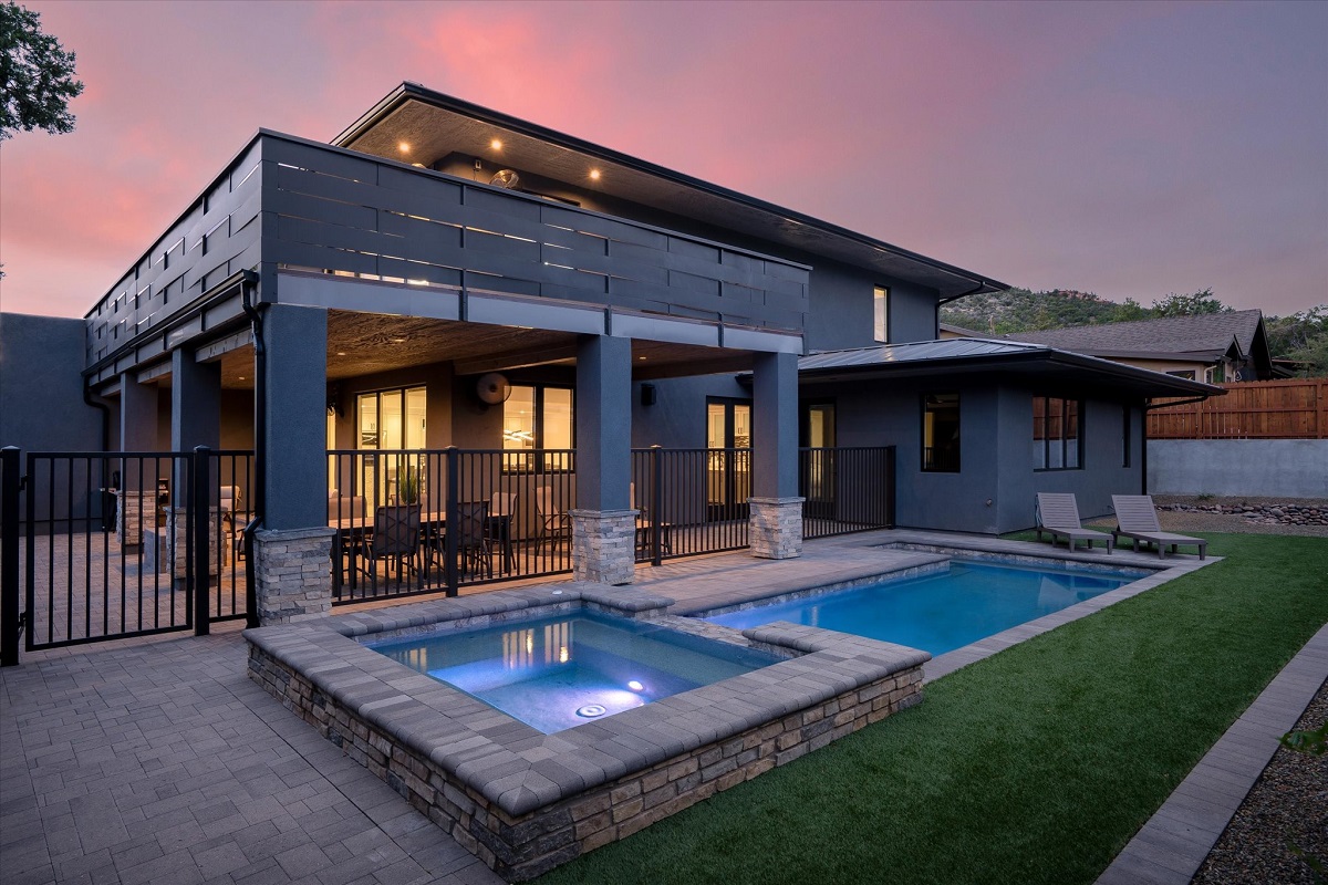 Luxury Scottsdale backyard with an illuminated pool and spa at night.