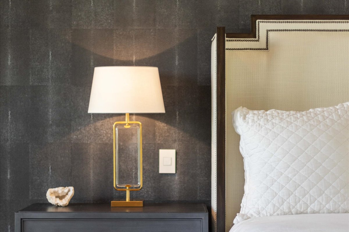 An elegant bedroom with warm lighting and a modern bedside lamp.