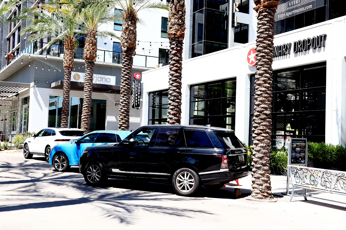 Scottsdale Quarter streetscape with palm trees, luxury vehicles, apartments, restaurants, and shops.
