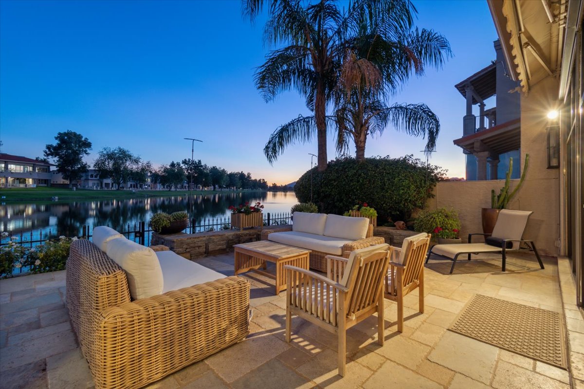 Waterfront patio at Las Palomas in McCormick Ranch with outdoor seating, palm trees, lake views, and evening light.
