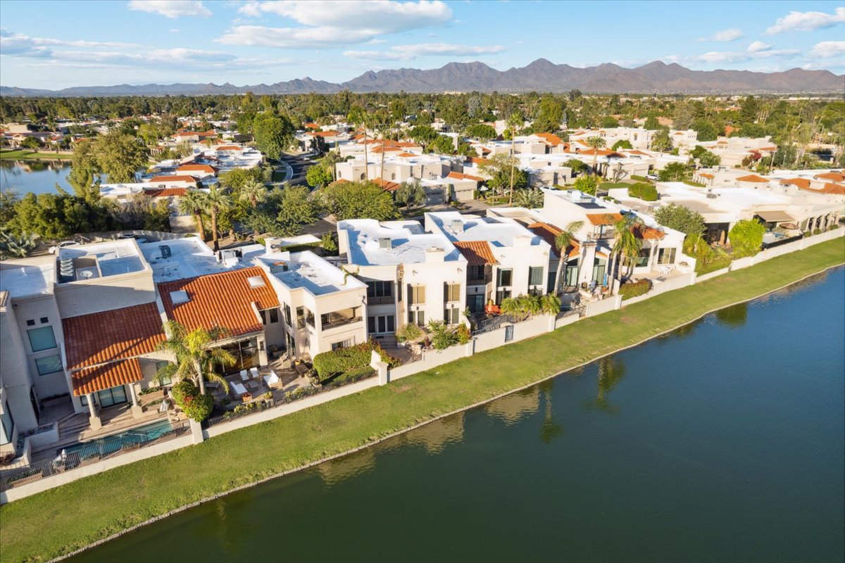 Aerial view of waterfront homes in McCormick Ranch with lake frontage, mature landscaping, and mountains across the Scottsdale skyline.