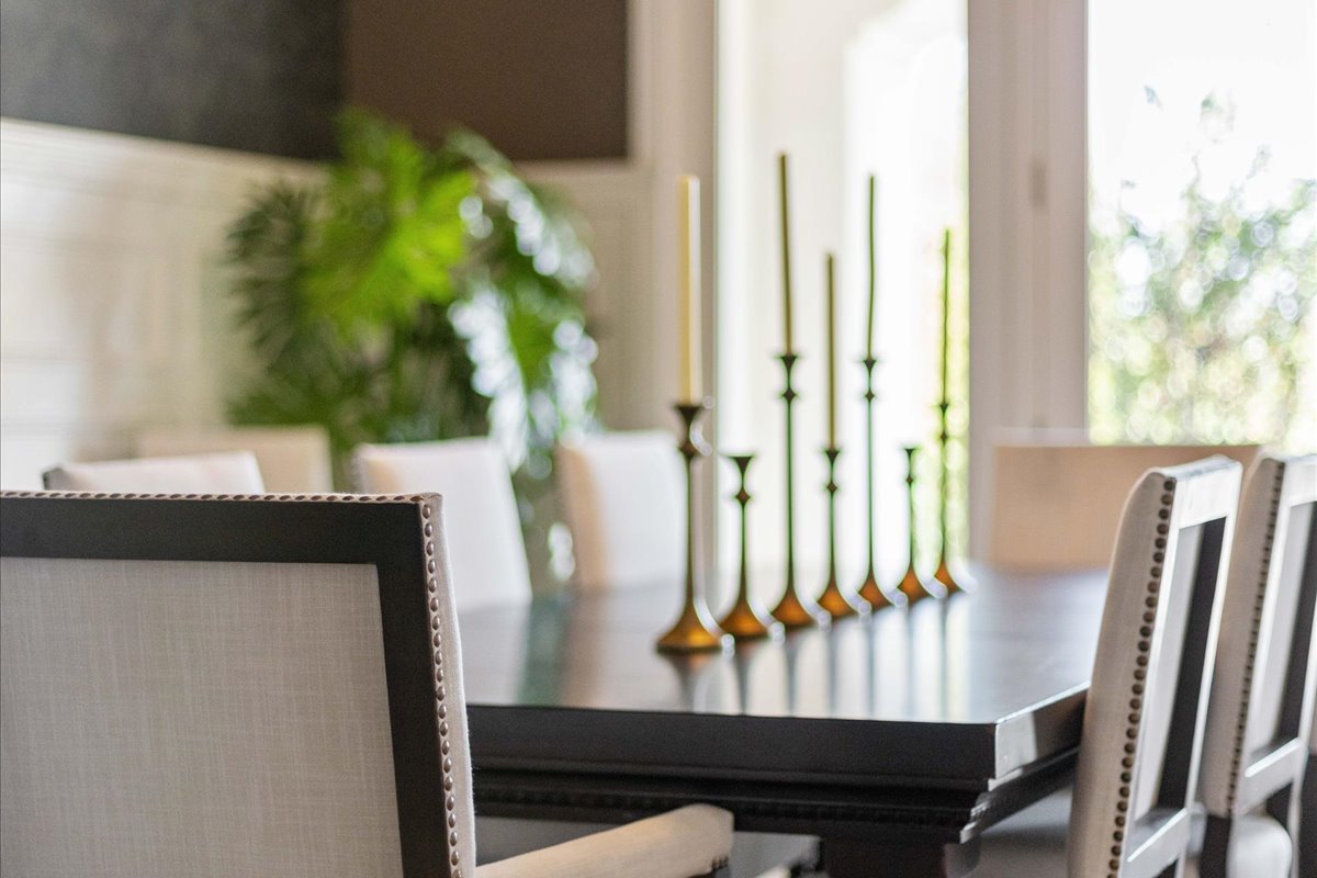 Sophisticated dining room featuring a dark wood table, upholstered chairs, and decorative brass candlesticks.