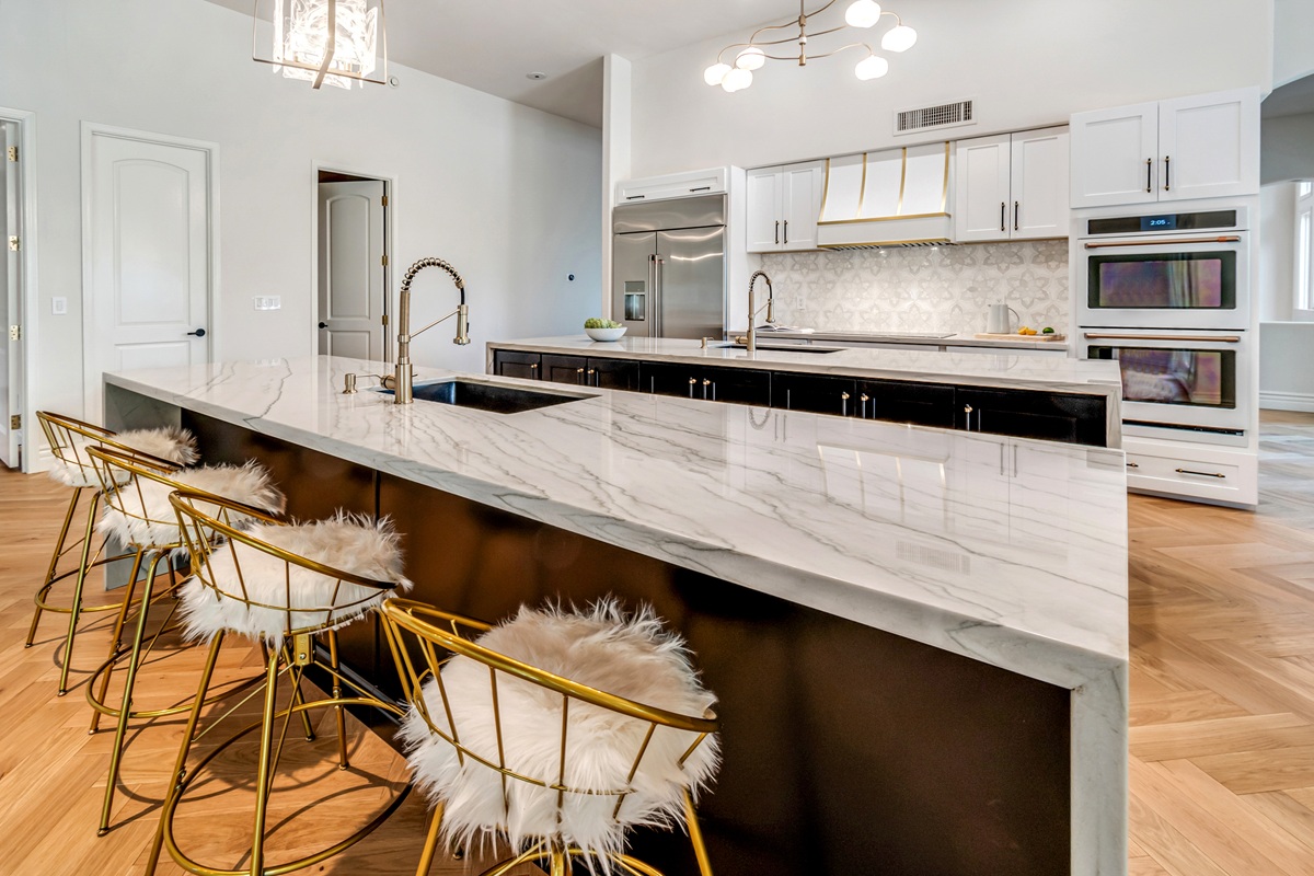 Elegant Silverleaf luxury home kitchen with a large marble island, custom cabinetry, gold-accented seating, and modern appliances.