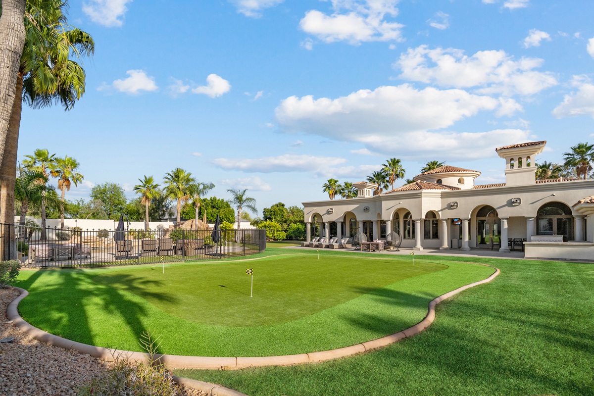 Scottsdale luxury estate with a private putting green, swimming pool, covered patio, and palm-lined landscaping.