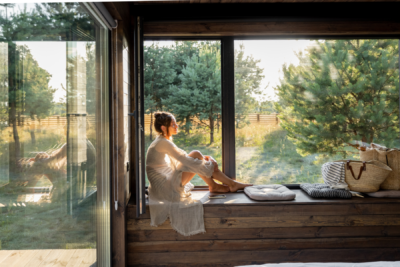 woman sits peacefully on a windowsill of the new home she owns