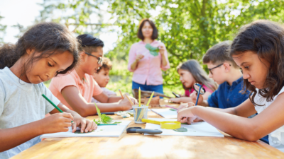 Kids at an outdoor summer camp doing crafts