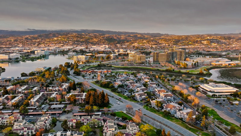 Evening aerial view of corporate buildings, waterfront condominiums, and residential neighborhoods in Redwood City, CA.