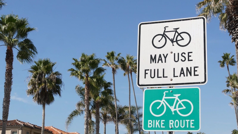 Bike Route green road sign in California, USA. Bicycle lane singpost. Bikeway in Oceanside pacific tourist resort. Cycleway signboard and palm. Healthy lifestyle, recreation and safety cycling symbol.