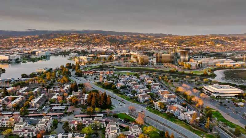 Evening aerial view of corporate buildings, waterfront condominiums, and residential neighborhoods in Redwood City, CA.
