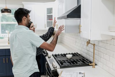 A couple inspecting kitchen cabinets.