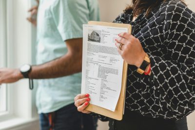 A real estate agent holding up an MLS listing information sheet.