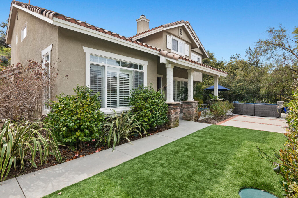 Malibu home exterior with a green lawn, shrubs, and a covered front porch