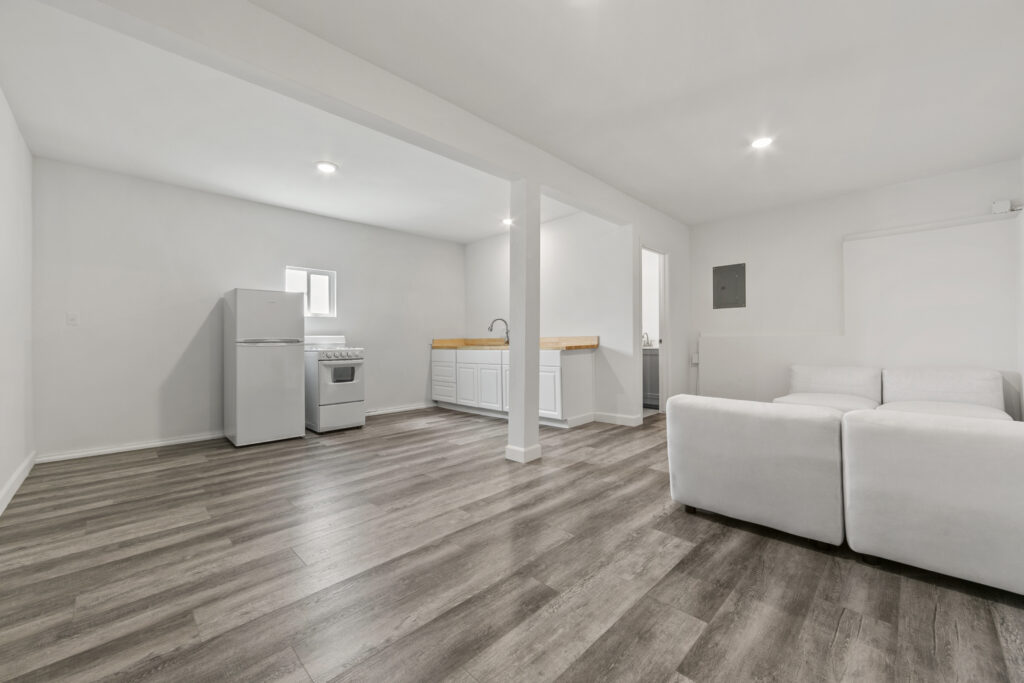 Interior of the Carbon Beach studio showing open layout with kitchen, living area, white cabinetry, and modern flooring