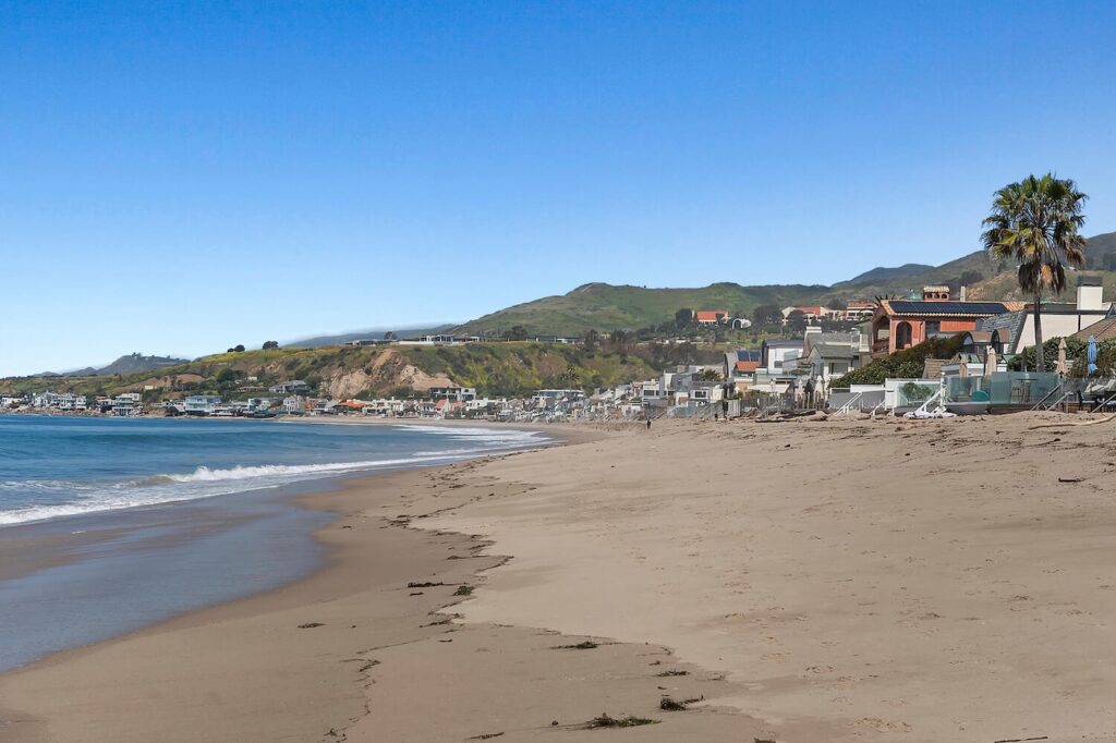 Beach-level view of Malibu Colony homes along the sandy shoreline