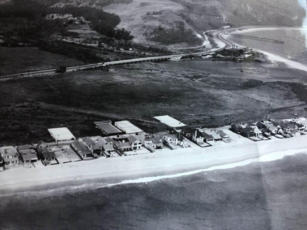 Historical black-and-white image of early Malibu Colony residences along the beach