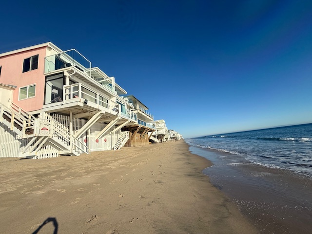 Row of Malibu Road beachfront homes on the sand with ocean views on a clear day