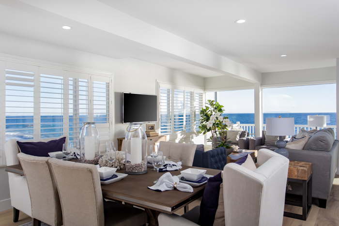 Bright oceanfront living and dining room inside a Malibu Road home with large windows and coastal views