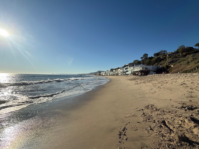 Wide sandy beach along Malibu Road with ocean views and beachfront homes in the distance