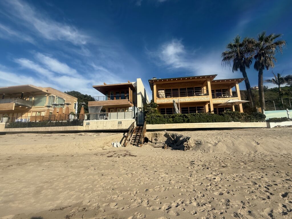 Malibu beachfront homes showing rooflines and water runoff paths where drainage meets sand and coastal erosion.