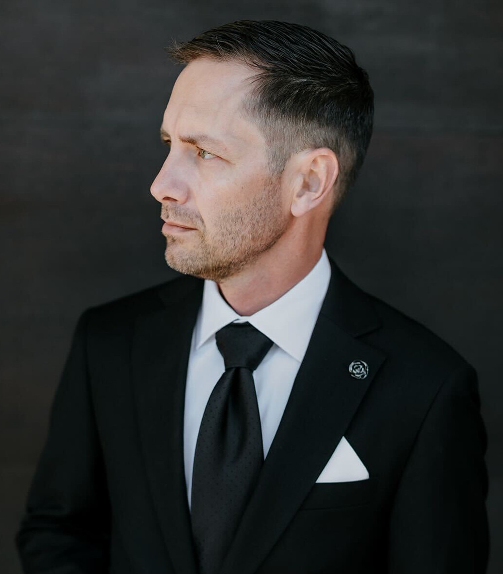 Side profile of Troy Palmquist in a black suit