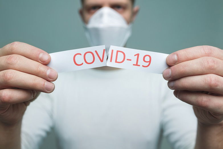 Worried man wearing a respiratory mask, holding the Coronavirus Covid-19 sign
