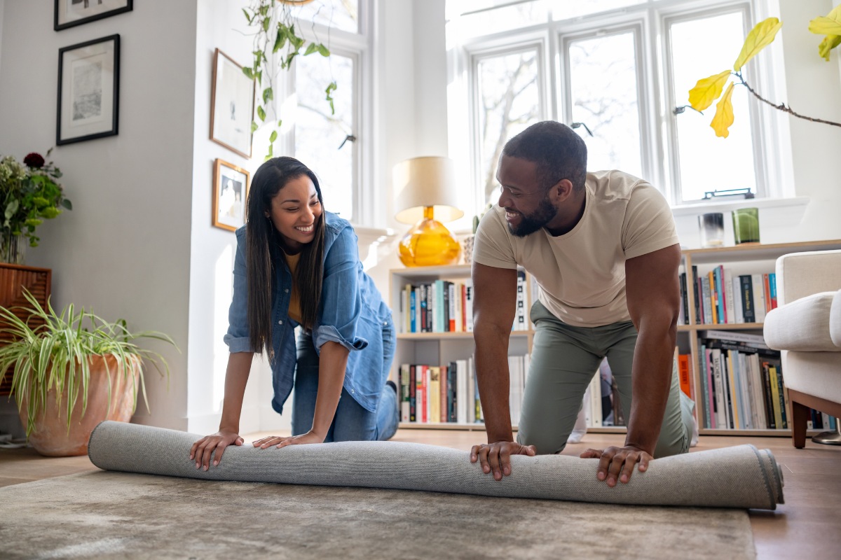 Happy couple unrolling a new carpet