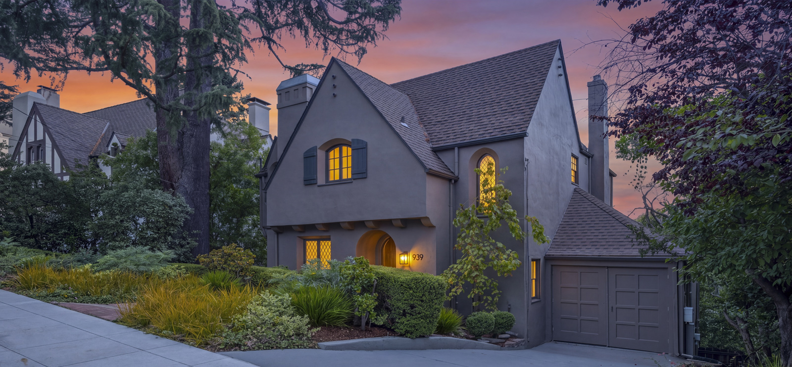 Tudor Revival-style home in Crocker Highlands, Oakland, at twilight, with steep gabled roofs, arched leaded-glass windows, and a landscaped front garden.