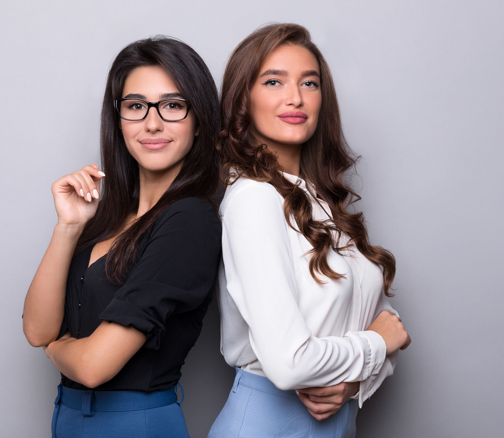 Two business women standing with their backs together